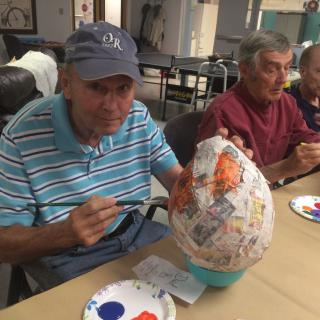 Elderly individuals engaging in a painting and crafting activity.
