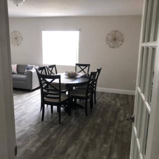 A cozy dining area with a round table and chairs, featuring minimalist decor and a large window for natural light.