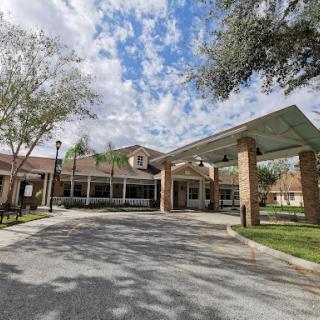 A welcoming entrance to a residential building under a bright, cloudy sky.