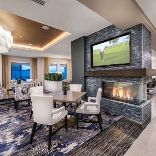 A modern lounge with a fireplace and television, featuring comfortable seating and stylish decor.