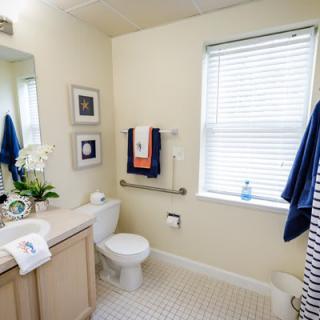 A well-lit and neatly organized bathroom featuring a sink, toilet, and towels.