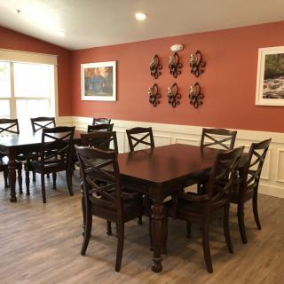 A cozy dining room with wooden tables and chairs, adorned with wall art.
