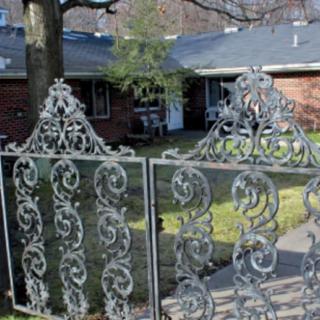 A decorative wrought iron gate in front of a residential house.