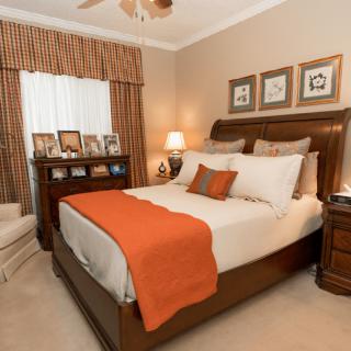 A cozy bedroom with orange accents and elegant furnishings.