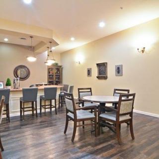 A cozy dining area with a bar counter, featuring wooden flooring and comfortable seating.