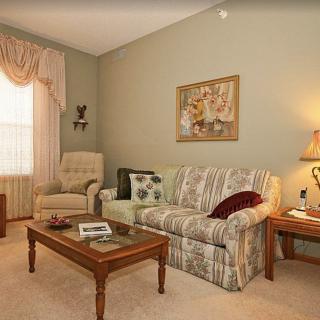 A cozy living room with a patterned sofa, armchair, coffee table, and soft lighting.