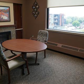 A small meeting room featuring a round table and two chairs, with a window offering an outside view.