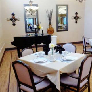 A well-decorated dining room featuring a set table and a black piano.