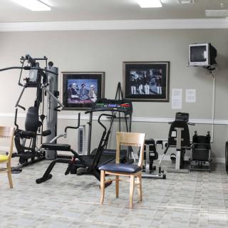 A small gym with various fitness equipment including a treadmill, exercise bike, and weight machine.