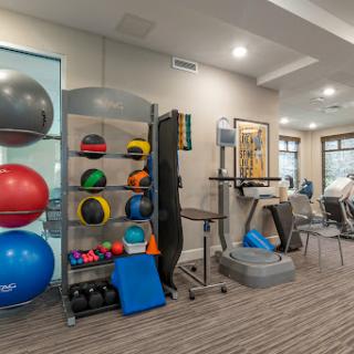 A well-equipped fitness area featuring various exercise equipment including stability balls, medicine balls, and a treadmill.