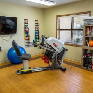 A therapy room equipped with a recumbent bike, exercise ball, and various fitness accessories.