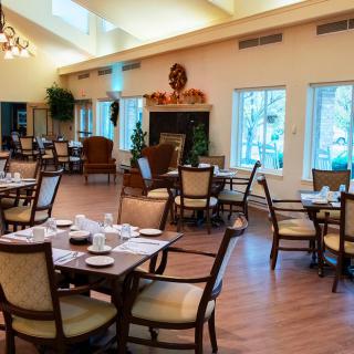 An elegant dining room setup with neatly arranged tables and chairs, featuring large windows and tasteful decor.