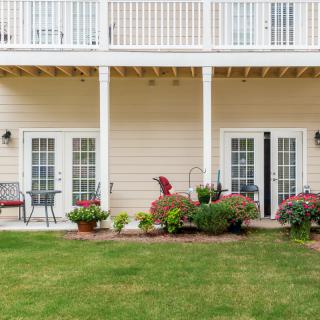 A two-story house with balconies, a well-maintained garden, and patio furniture.