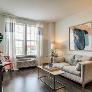 A modern living room with a cozy sofa, coffee table, and large artwork.