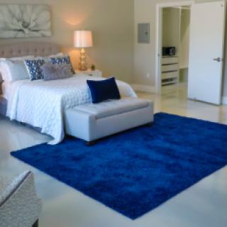 A modern bedroom featuring a large blue rug and stylish decor.