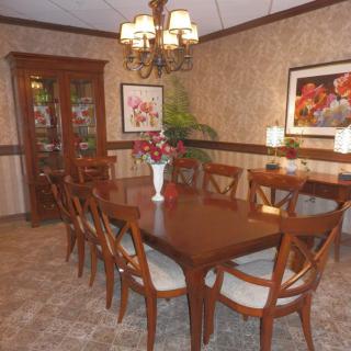 A dining room with a large wooden table surrounded by chairs, a chandelier above, and artwork on the walls.