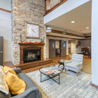 A cozy living room featuring a stone fireplace, modern furniture, and warm decor.