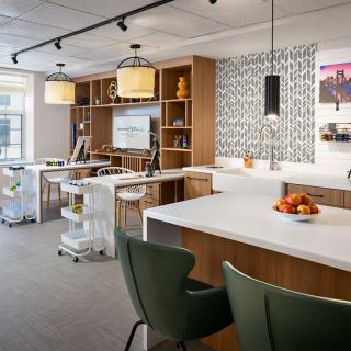 A modern kitchen interior with a central island, stylish seating, and decorative lighting.