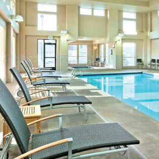A serene indoor swimming pool area featuring comfortable lounge chairs, perfect for relaxation and leisure.