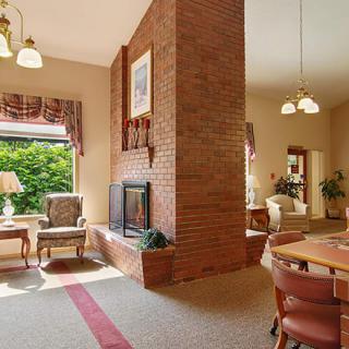 A cozy living room featuring a brick fireplace, traditional furniture, and a dining area.