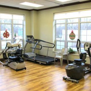 A well-lit gym with exercise equipment including a treadmill and stationary bikes.