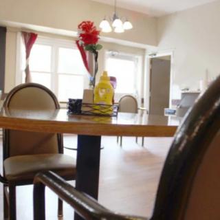 A cozy dining room with a table set featuring condiments and a vase with flowers.