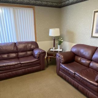 A cozy living room with leather sofas and a small lamp on a table.