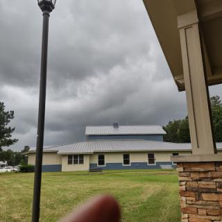 A view of a cloudy sky over buildings with a grassy area in the foreground.