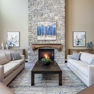 A modern living room with a stone fireplace, neutral-toned sofas, and minimalist artwork.