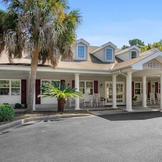 A single-story residential building with a porch and palm tree in the front yard.