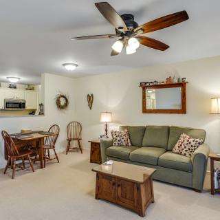 A cozy living room with a sofa, wooden coffee table, and dining area in the background, featuring a ceiling fan and warm lighting.
