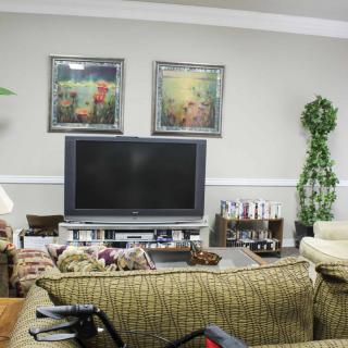 A cozy living room with a large television, comfortable sofas, and decorative artwork on the walls.