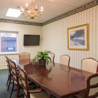 A well-furnished conference room featuring a large wooden table, elegant chairs, and ambient lighting.