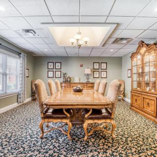 A cozy dining room with an elegant wooden table and upholstered chairs, featuring a chandelier and decorative cabinet.