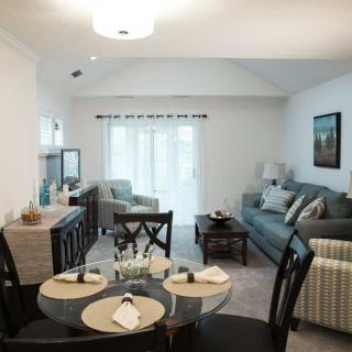 A cozy and modern living room with an adjacent dining area, featuring comfortable furniture and bright lighting.