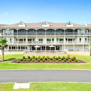 A large multi-story residential building with a well-maintained lawn and balconies.