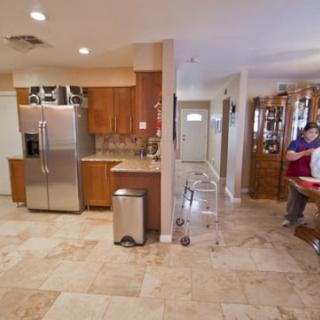 A modern kitchen interior with stainless steel appliances, wood cabinetry, and tile flooring.