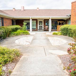 A welcoming entrance to a residential building, featuring well-maintained landscaping and a clear pathway.