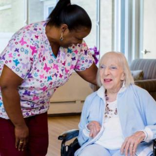 A healthcare worker interacting with an elderly woman in a wheelchair, demonstrating care and support.