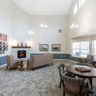 A spacious and well-lit living room with a fireplace, high ceiling, and comfortable seating.
