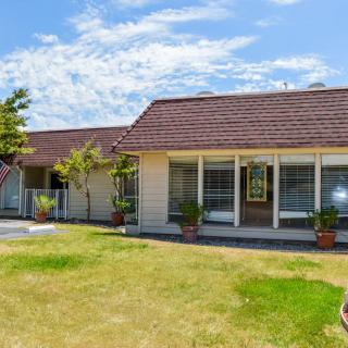 A single-story house with a large lawn and clear blue sky.