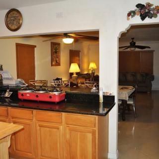 A cozy kitchen with wooden cabinets overlooking a dining and living area.