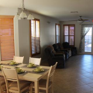 A cozy dining and living area with a wooden dining table, chairs, and a row of comfortable sofas by the windows.