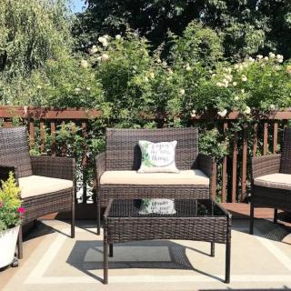 A cozy outdoor patio set with chairs and a table surrounded by lush greenery.
