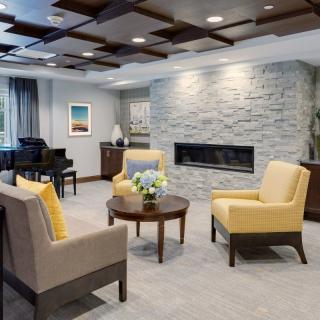 A modern living room with a stone fireplace, featuring yellow and beige seating.