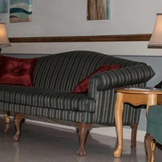A living room setting featuring a striped sofa with red cushions, flanked by wooden side tables and lamps.