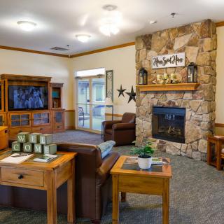 A cozy living room with a stone fireplace and comfortable furniture.