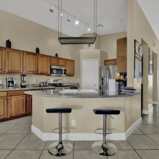 A modern kitchen with wooden cabinets, a central countertop, and sleek bar stools.