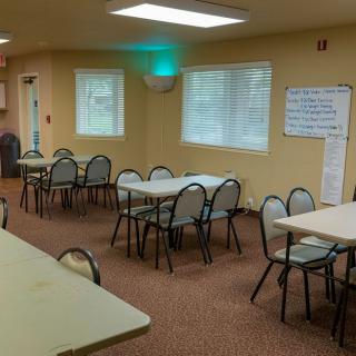 An empty meeting room with tables and chairs arranged for a conference or gathering.