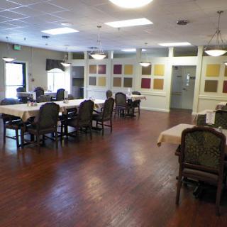 A spacious dining room setup with tables and chairs arranged, featuring decorative wall panels.
